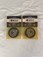 Two NHL collectible hockey pucks in original packaging on white cloth background. The left puck features a blue and white team logo; the right puck features a Stanley Cup 1993-1994 logo.