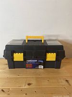 Front view of Mastercraft black plastic toolbox with label attached and yellow handle and latches