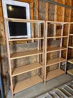 Two beige metal shelving units positioned side-by-side with five shelves each, shown against unfinished wall with window.