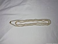 Two long white pearl necklaces laid out showing length and clasps