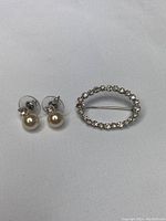 Pearl earrings and brooch on white background, showing full lot.
