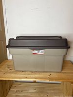 Side view of closed Rubbermaid storage tote, showing label and lid design.