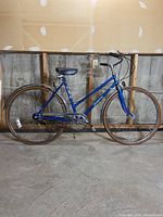 Full side view of the vintage blue cruiser bike showing frame, tires, saddle, and drivetrain.