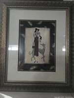 Framed print featuring a woman in a long dress holding a dog. Ornate frame with metallic finish.