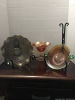 Full display of six carnival glass items placed on wooden furniture against white backdrop