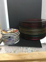 Stack of red, gold, and green metallic charger plates next to a stack of party plates in themed designs.