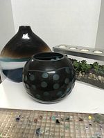 Front view of the three decorative items showing tall vase, round vase with polka dots, and terrarium with artificial succulents and stones