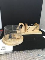 Wooden guillotine slicer and cheese curl girouette set on black background.