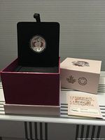 Canadian silver coin in black velvet holder inside pink box with certificate of authenticity.