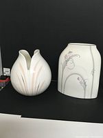 Photo of two Royal Doulton vases shown side by side on a black surface with dark backdrop.