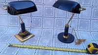 Two vintage Mid-Century Modern banker’s lamps shown with measuring tape for scale. Both have black glass curved shades, marble columns, brass fittings. One has square brass base; the other round.