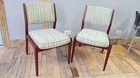 Two Danish Rosewood chairs with striped upholstery, set on a wooden floor against a wall with power outlets visible.