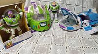 Three Buzz Lightyear figures alongside two vehicles displayed on table