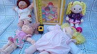 Three dolls including two Cabbage Patch Kids dolls and one baby doll with yellow yarn hair, along with a yellow Cabbage Patch Kids accessory case.