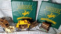 Two plastic stagecoach toys with horses in front of two green padded Evergreen Rodeo stadium seats