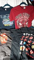 All four apparel items displayed: Rolling Stones hoodie and T-shirt, Eagles T-shirt, Bob Seger T-shirt