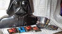 Darth Vader shaped collectible case with stacks of Star Wars character cards spread out.