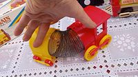 Photo showing red and yellow Fisher-Price train engine connected by metal slinky to yellow caboose, held by hand for scale