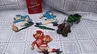 Lot arranged on lace patterned tablecloth showing three football kids wall hangers, gasoline oil tin vertically positioned, and horse-drawn wagon model in view.
