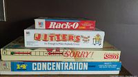Stacked boxes of four vintage board games: Rack-O, Jitters, Sorry, Concentration