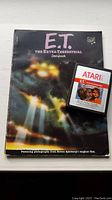 E.T. The Extra-Terrestrial storybook with Atari 2600 game cartridge placed on top, showing front covers.