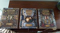 Front covers of the three Dungeons & Dragons core rule books (Player's Handbook, Dungeon Master's Guide, Monster Manual) arranged side by side on a wooden surface.