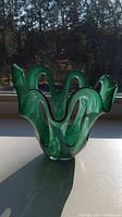 Front view of teal/green hand blown glass vase showing ruffled edges and swirl pattern