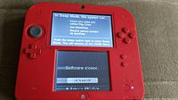 Front view of Nintendo 2DS handheld with screens on showing software close screen and fuzzy bottom screen