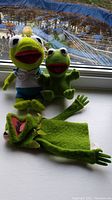 All three Kermit the Frog items displayed on a windowsill, showing size and condition comparison.