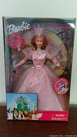Front view of Glinda Barbie in original box showing doll dressed in pink with Wizard of Oz logo at bottom left.