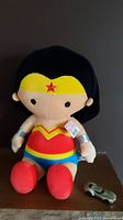 Wonder Woman plush stuffed sitting toy with black hair, red and yellow costume, and silver bracelets