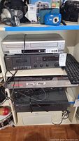 Multiple electronics and keyboard on shelving, front view