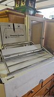 Stainless steel towel rack, elongated bowl seat box behind it, wooden framed mirror partially visible.