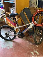 Full view of Diamondback mountain bike along with three skateboards and red hula hoop in background