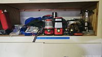Wide view of shelving showing various camping supplies including lanterns, daybag, and canteen