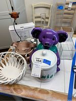 Entire lot showing multiple items including ceramic cookie jars, clear glass vases, a woven basket, and candleholders on a white tiled surface.