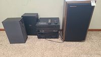 Photo showing a stack of black stereo components with accompanying speakers including a large Cerwin-Vega speaker with wood side panels and black speaker grills.