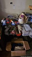 Top metal shelf with various small hardware items, tapes, and hand tools