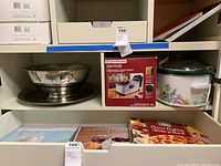 Shelf with Hamilton Beach deep fryer box, stainless steel mixing bowls, and crock pot with floral design
