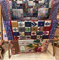 Three handmade rectangle quilts displayed on a wooden stand showing sizes and designs.