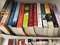 Two images showing paperback fiction novels in a box, authors include Holly Chamberlin, Susan Wiggs, Genevieve Graham, Ellen Keith among others.