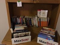 Books arranged on wooden shelves with visible author names and titles in both soft and hard covers.