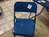 Blue metal folding chair with metal seat and backrest, minimal wear visible on seat.