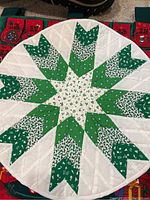 21x21 inch round green patterned quilted item, featuring a star-like design with green and white patches