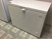 Front and side view of the white Amana chest freezer with closed lid, showing the size and overall condition.