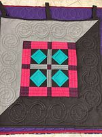 Close-up of the black and pink quilt with turquoise accents and machine-stitched spiral pattern.