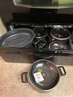 All pots, pans, and roasting pan shown inside oven and on stove surface, shows assortment and condition