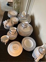 Full set of Royal Doulton Valleyfield china arranged on table showing plates, bowls, cups, saucers, and tea pot with lid, back view of tea pot with pattern visible.