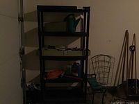 Full view of the black plastic shelving unit with five shelves placed in a garage setting, showing the structure and support of the shelves.