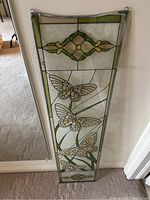 Full view of stained glass panel showing overall size, shape, and design with butterflies and floral elements